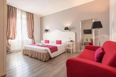 a hotel room with a bed and a red couch at Residenza Castrense in Rome