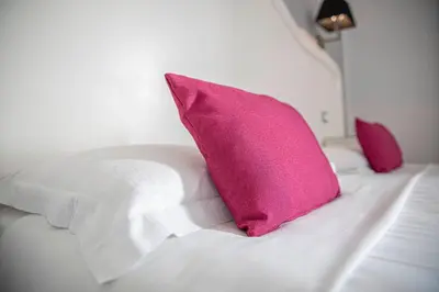 a white bed with a pink pillow on it at Residenza Castrense in Rome