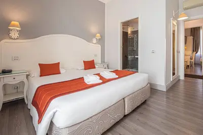 a bedroom with a large white bed with an orange blanket at Suite Castrense in Rome