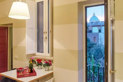 a kitchen with a window and a table with flowers at La Porta Rossa di Borgo - Vatican Luxury Suite in Rome