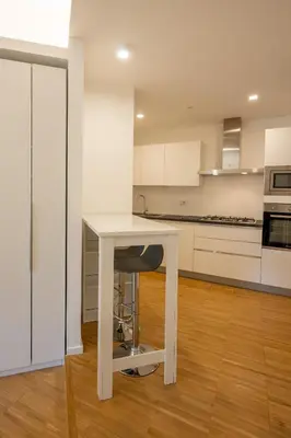 a white kitchen with a table and a chair at La casa di Livia in Rome