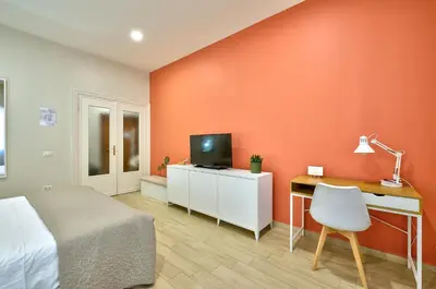 a bedroom with a bed and a tv and a desk at Marigiò Vatican Apartment in Rome