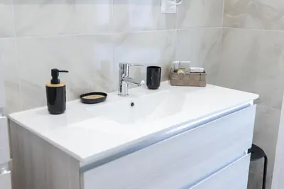 a white bathroom sink with two cups and a faucet at Trastevere Magic House Luxury Suite in Rome