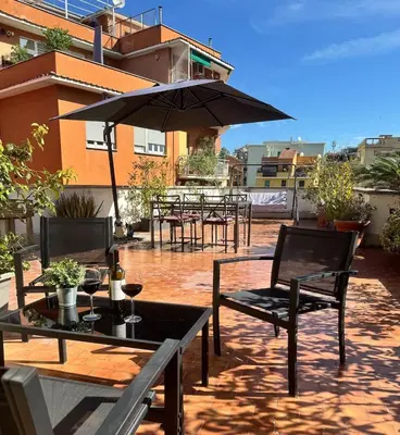a patio with tables and chairs and an umbrella at Casa Mapi in Rome