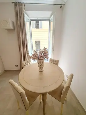 a dining room table with chairs and a vase with flowers at Suite della Vite 27 in Rome