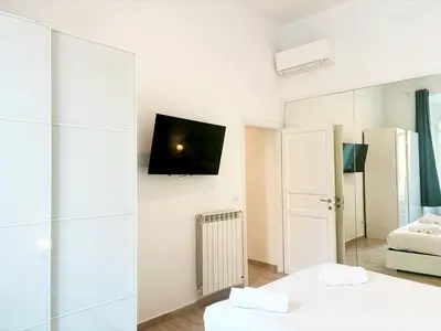 a white room with two beds and a tv on a wall at DaliTourism - Vatican Apartment 193 in Rome