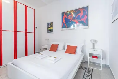 a white bedroom with a white bed with orange pillows at Oscar Apt near Landmarks and Colosseum in Rome