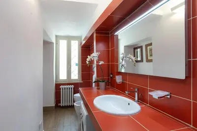 a bathroom with a sink and a red wall at Amazing Via del Babuino - Piazza del Popolo in Rome