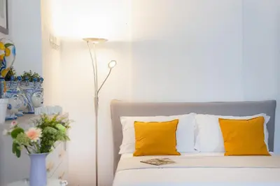 a bedroom with a bed with yellow pillows and a lamp at Amazing Via del Babuino - Piazza del Popolo in Rome