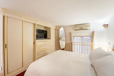 a bedroom with a white bed and a television at Studio d'Artista, Elegante Loft nel Cuore di Roma in Rome