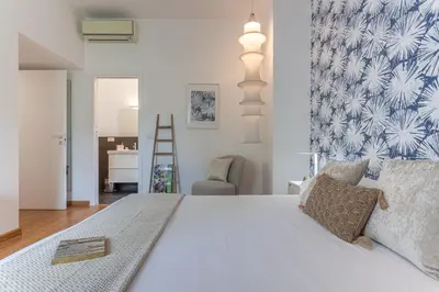 a bedroom with a white bed with a blue and white wallpaper at Minerva - Elegant New Classic close to Vatican in Rome