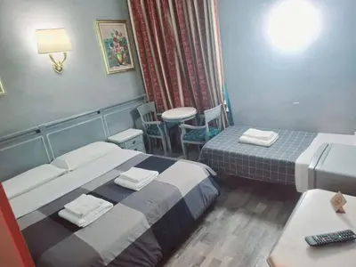 a hotel room with two beds and a table at Hotel Positano 2 in Rome