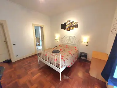 a bedroom with a white bed and a wooden floor at Holiday Room Naiadis in Rome