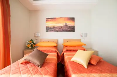 a bedroom with two beds with orange pillows at Di Fronte alla Cupola in Rome