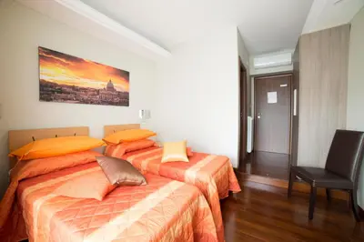 a bedroom with two beds with orange sheets and a chair at Di Fronte alla Cupola in Rome