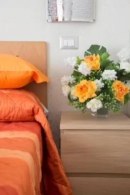 a vase of flowers on a dresser next to a bed at Di Fronte alla Cupola in Rome