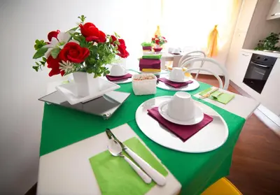 a green and white table with red roses on it at Di Fronte alla Cupola in Rome