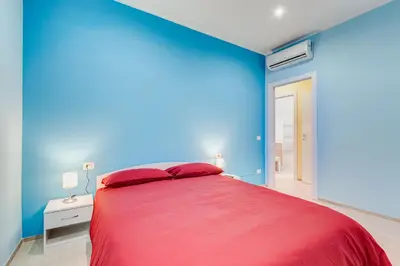 a bedroom with a red bed with a blue wall at Monteverde Cozy Apartment in Rome