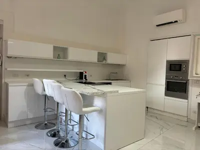 a white kitchen with white counter tops and bar stools at DOLCE VITA VIMINALE ROOM in Rome