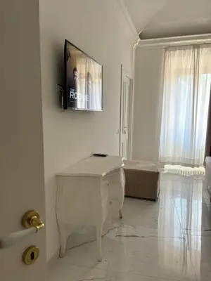 a white living room with a tv on the wall at DOLCE VITA VIMINALE ROOM in Rome
