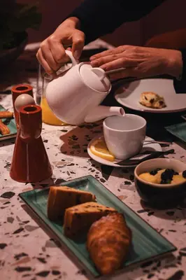 a person pouring tea into a teapot on a table at THE STEPS Hotel - by Eitch Collection in Rome