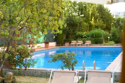 a large blue swimming pool with chairs and trees at Laura Sweet Home con Piscina in Rome