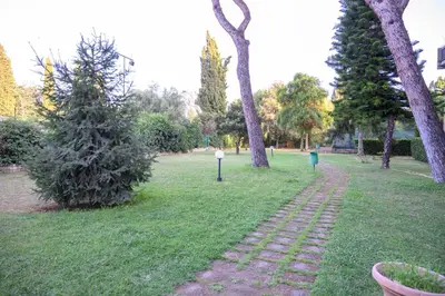 a brick path in a park with a tree and trees at Laura Sweet Home con Piscina in Rome