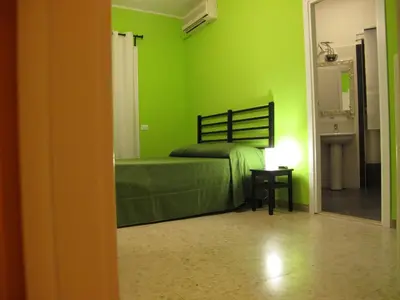 a green bedroom with a bed and a sink at Arches Inn in Rome