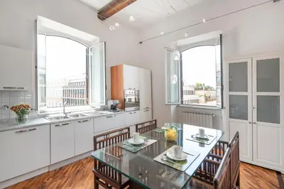 a kitchen with a table and chairs and windows at Relais Quinto Piano in Rome