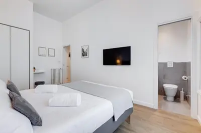a white bedroom with a bed and a bathroom at Colonna Luxury Apartment in Rome