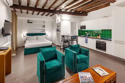 a bedroom with a bed and two green chairs at Casa Annamaria al Pantheon in Rome