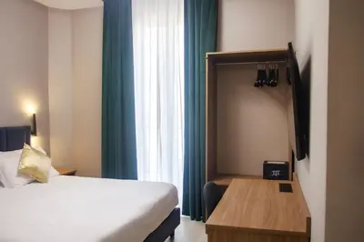 a bedroom with a bed and a desk and a window at Vatican museum guest house in Rome