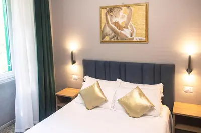 a bedroom with a bed with gold pillows and a painting at Vatican museum guest house in Rome