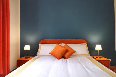 a bed with two orange pillows and a blue wall at Charming Vatican LargeApt by YH in Rome