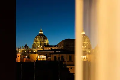 a view of the domes of a city at night at the happy suite, just renovated in Rome