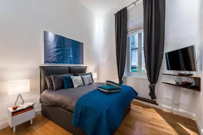 a bedroom with a bed with a blue blanket and a tv at Argentina Residenza Style Hotel in Rome