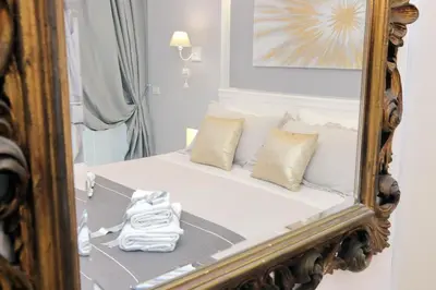 a mirror reflecting a bed with pillows on it at Roman Holiday Suites in Rome
