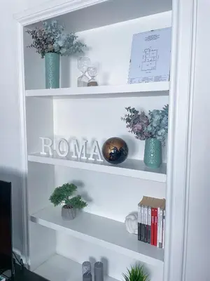 a white book shelf with two blue vases and flowers at Domus Montebello in Rome