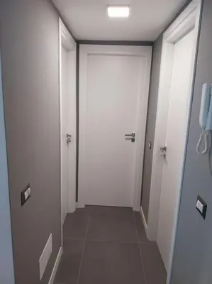 a hallway with a white door and a tile floor at j u b i l e h o u s e R o m e in Rome