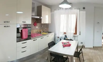 a kitchen with white cabinets and a table with chairs at casa di lella ai musei vaticani in Rome