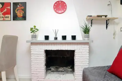a living room with a brick fireplace with a clock at Al moretto in Rome