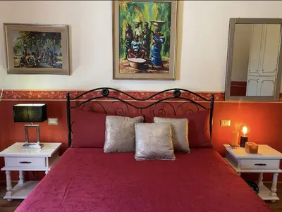a bedroom with a red bed with two tables and a mirror at DOMUS ANNIA Guest House, The Amazing Colosseum in Rome