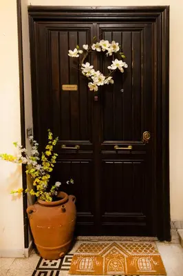 a black door with a vase with flowers in front of it at La Casa di Vittorio boutique Ottaviano San Pietro in Rome