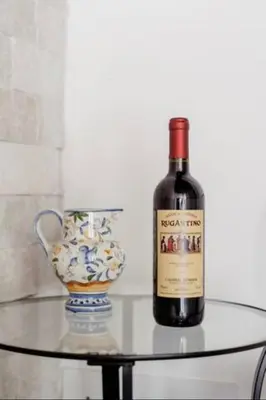 a bottle of wine on a glass table next to a vase at Trastevere's Nest in Rome
