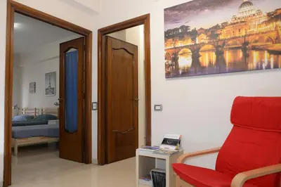 a room with a red chair and a bedroom at Emilios home Triple room in our cozy and comfortable establishment in Rome