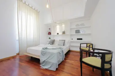 a white bedroom with a bed and a chair at Segneri Viale Trastevere in Rome