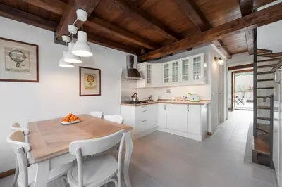a kitchen with white cabinets and a wooden table and chairs at Charming patio house in San Lorenzo in Rome
