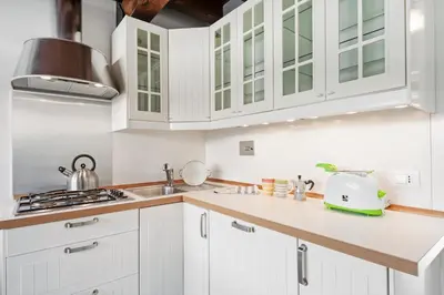 a white kitchen with white cabinets and a sink at Charming patio house in San Lorenzo in Rome