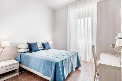 a white bedroom with a blue bed and a window at APARTMENT IN TRASTEVERE in Rome