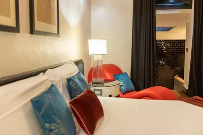a bedroom with a bed and a chair and a lamp at Cloe Suite - A due passi da Villa Borghese in Rome